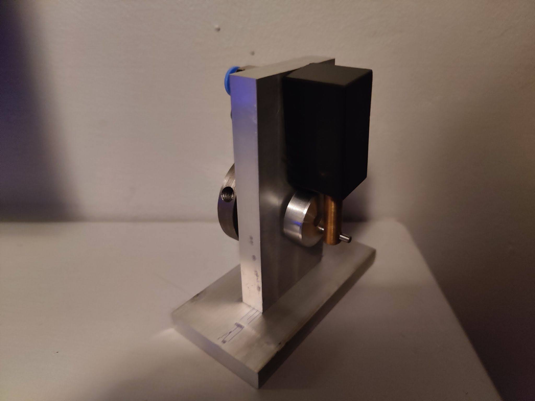 A machined wobbler engine made from brass, aluminum, and steel, mounted on an aluminum base.